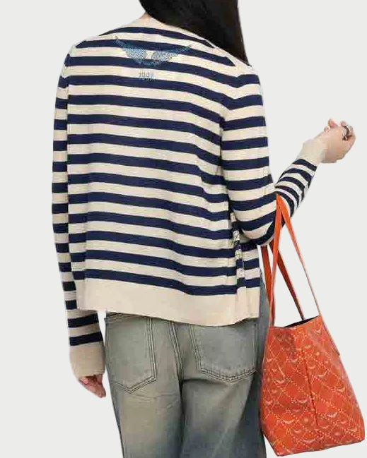 Person wearing a striped sweater and jeans, holding an orange bag on a white background