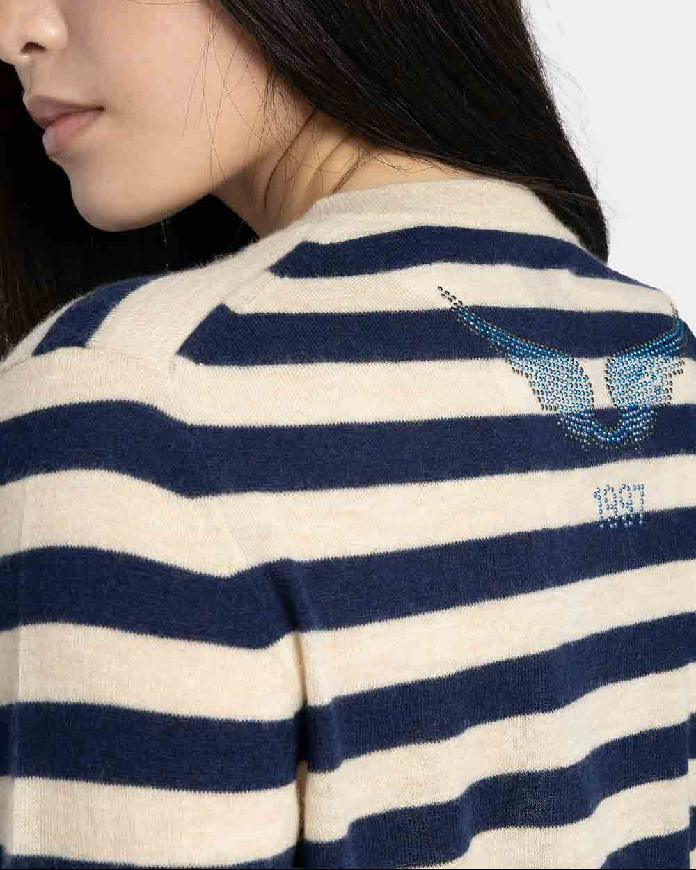 Close-up of a person wearing a blue and white striped sweater with a logo on a white background