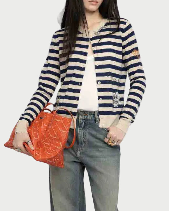 A woman wears the Zadig & Voltaire Missya Stripe Sweater over a white top with faded jeans, holding an orange patterned handbag. Her face is partially out of frame.