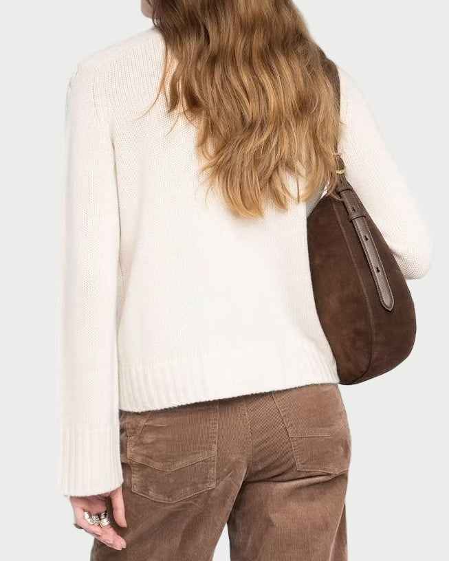 Woman wearing brown corduroy pants and a beige sweater on a white background