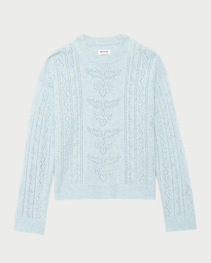 A light blue knit sweater with vertical cable and geometric patterns, laid flat against a light gray background.