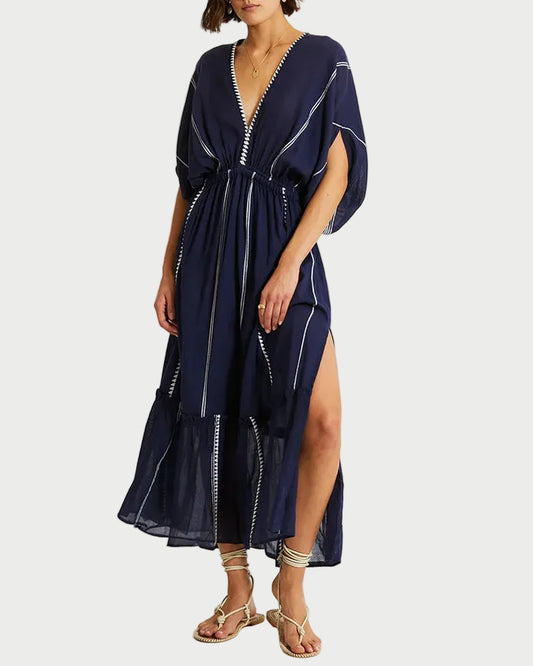 Woman wearing a navy blue dress with a slit on a white background