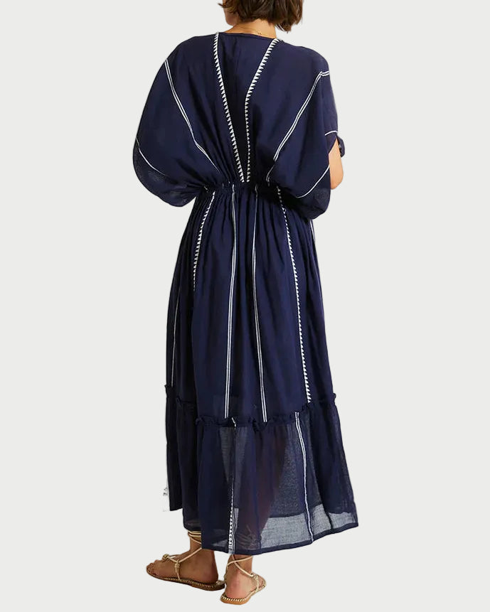 Woman wearing a navy blue dress with white trim on a white background