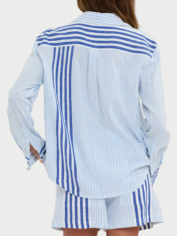 Woman wearing a blue and white striped shirt and skirt set against a plain background