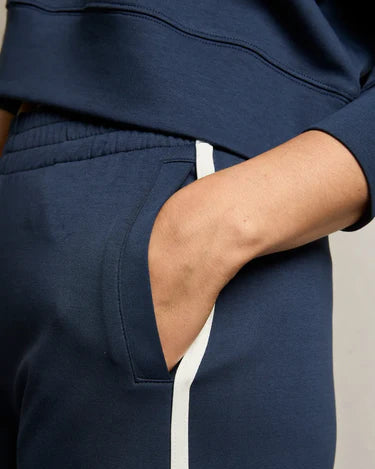 A person is wearing the Perfectwhitetee Mikos Wide Leg Pant by perfectwhitetee in navy with a white stripe, their right hand in the pocket. The matching sweatshirt is partially visible.