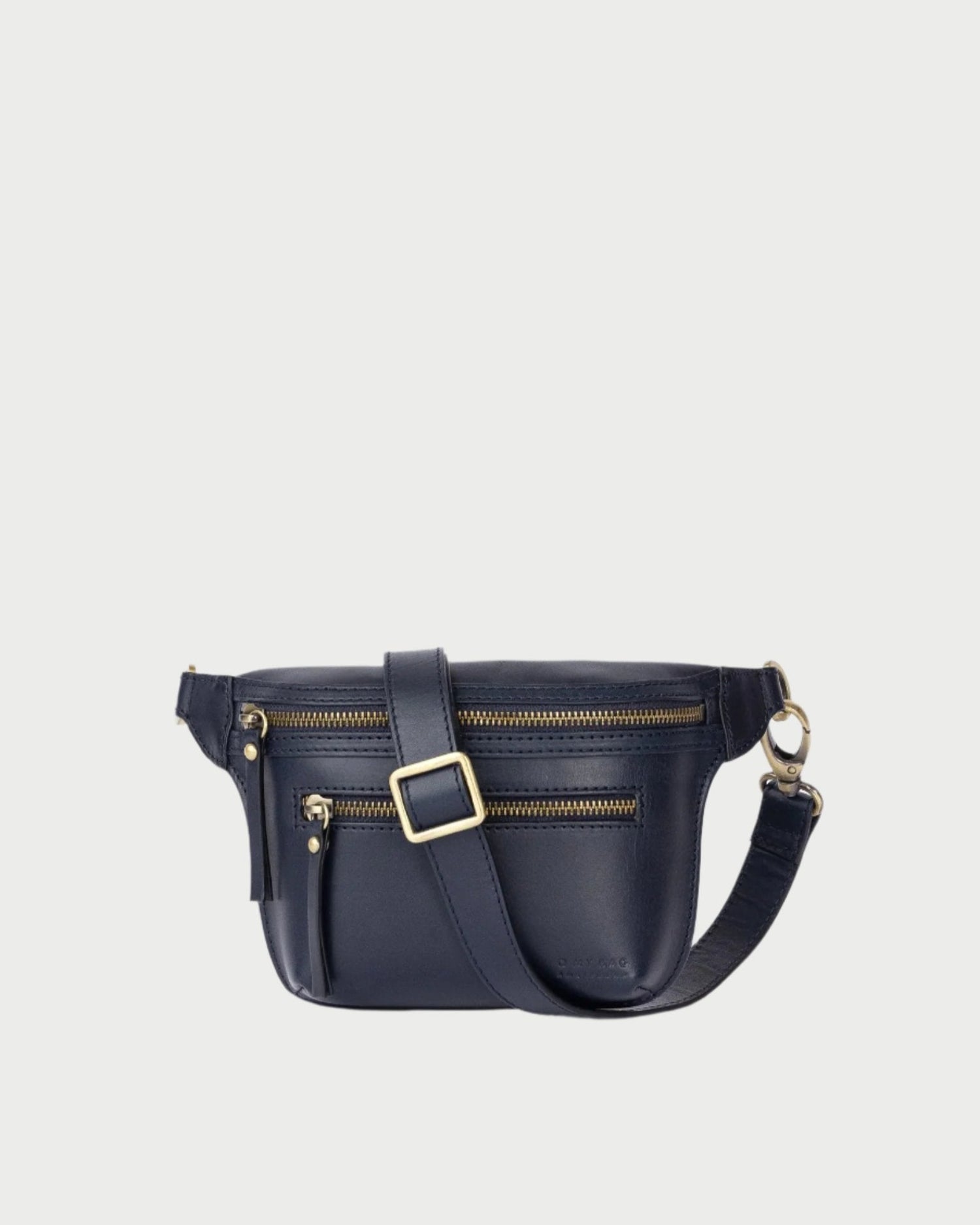 The Beck's Bum Bag in Midnight Blue from O MY BAG features a sleek design with two front zippered compartments, a small pocket, and an adjustable strap with gold buckle and clasp. The bag is showcased against a clean white background, blending elegance with everyday practicality.