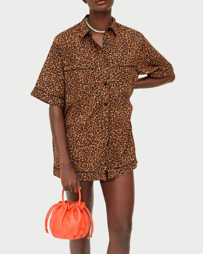 Person wearing a leopard print shirt holding an orange bag on a white background