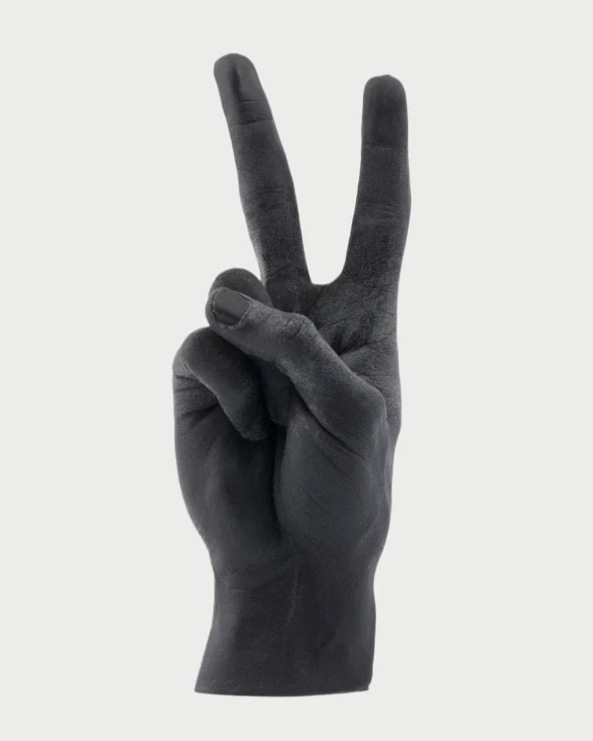 A black, handmade Candle Hand Victory "Peace" by 54° Celsius shaped like a life-sized hand giving a peace sign with two wicks at the fingertips, set against a plain white background.