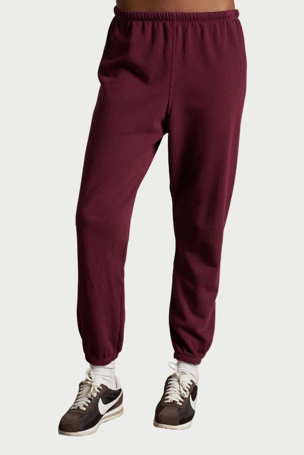 Maroon sweatpants worn by a person on a plain background