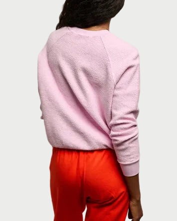 Person wearing a pink sweater and red pants against a plain background