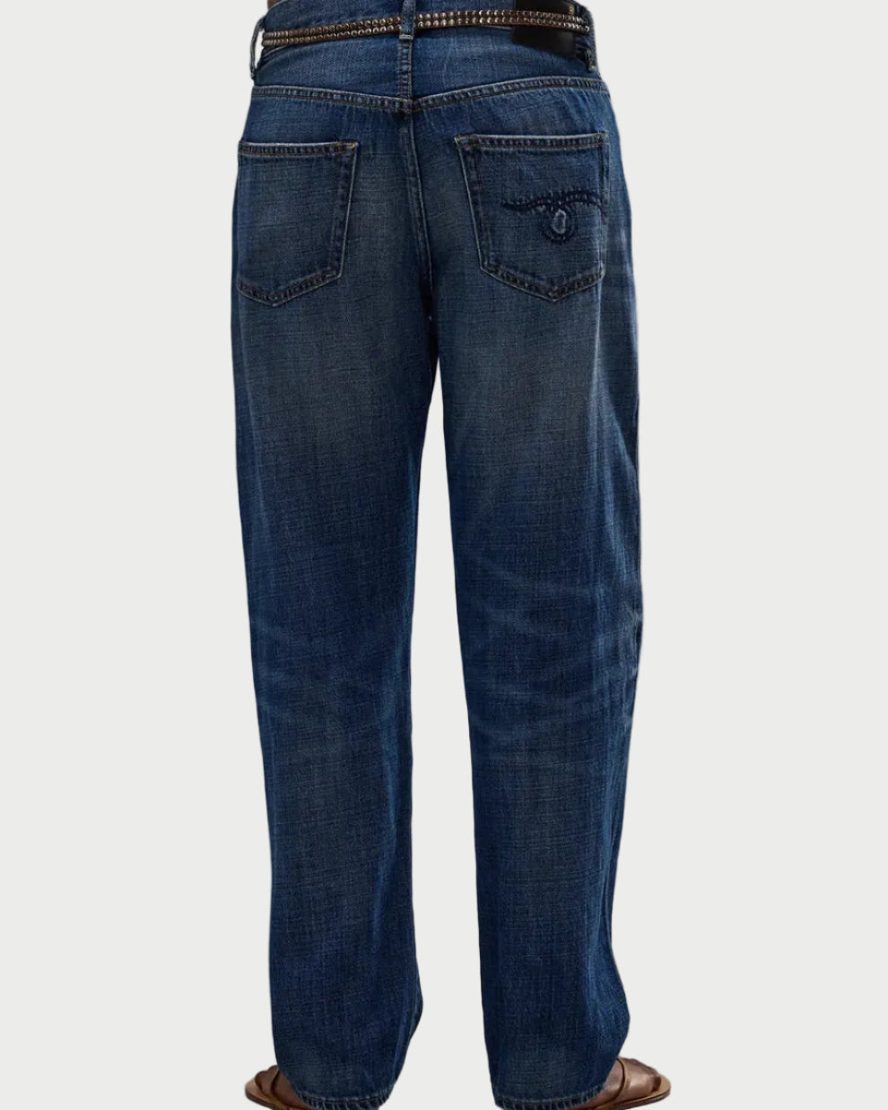 A person is shown from the back wearing R13 Boyfriend Jean by R13 with a black belt and brown sandals. The mid-rise, relaxed fit jeans have two back pockets, including one with a buttoned flap, against a plain white background.