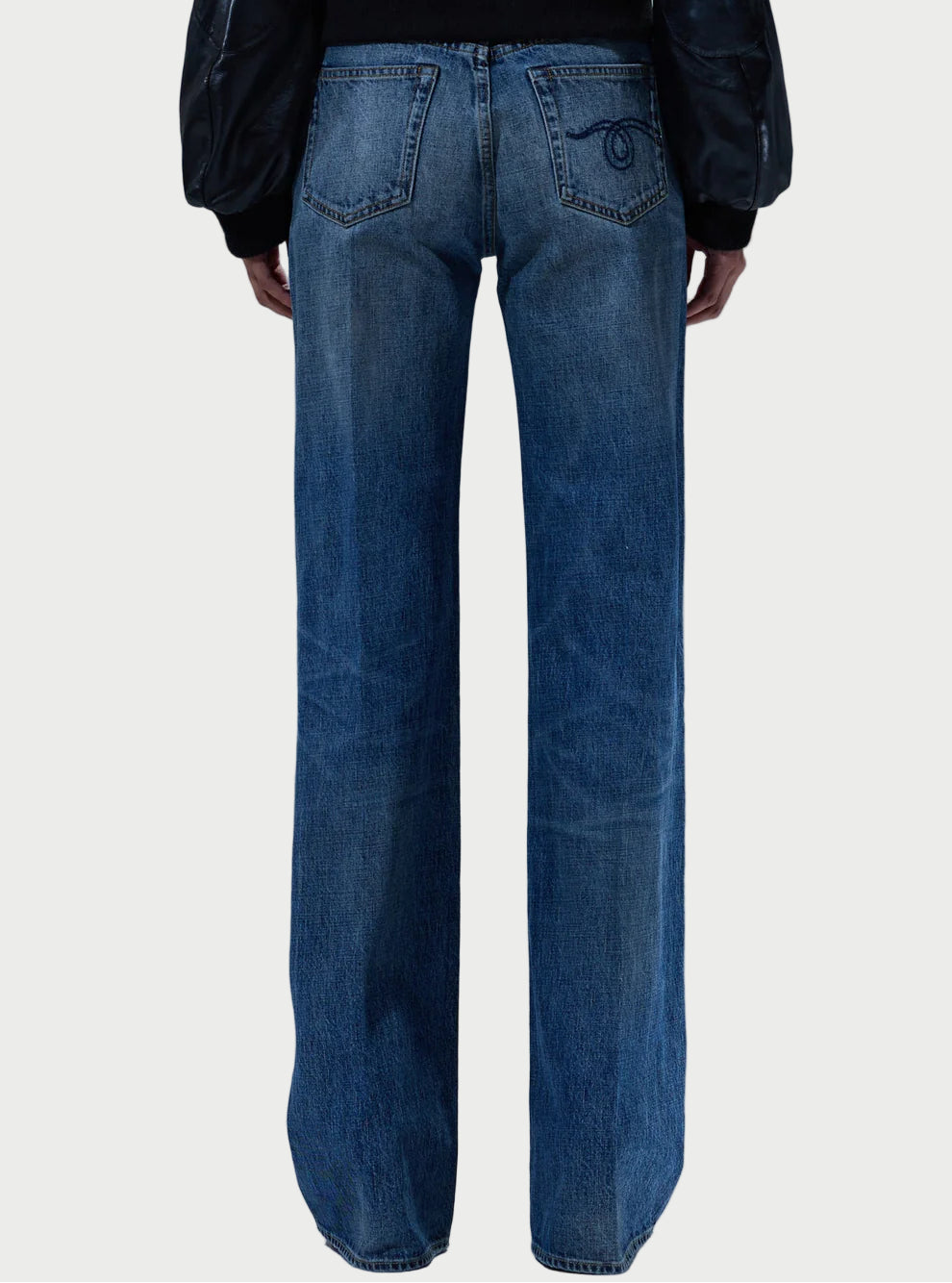 Person wearing blue jeans with a plain background