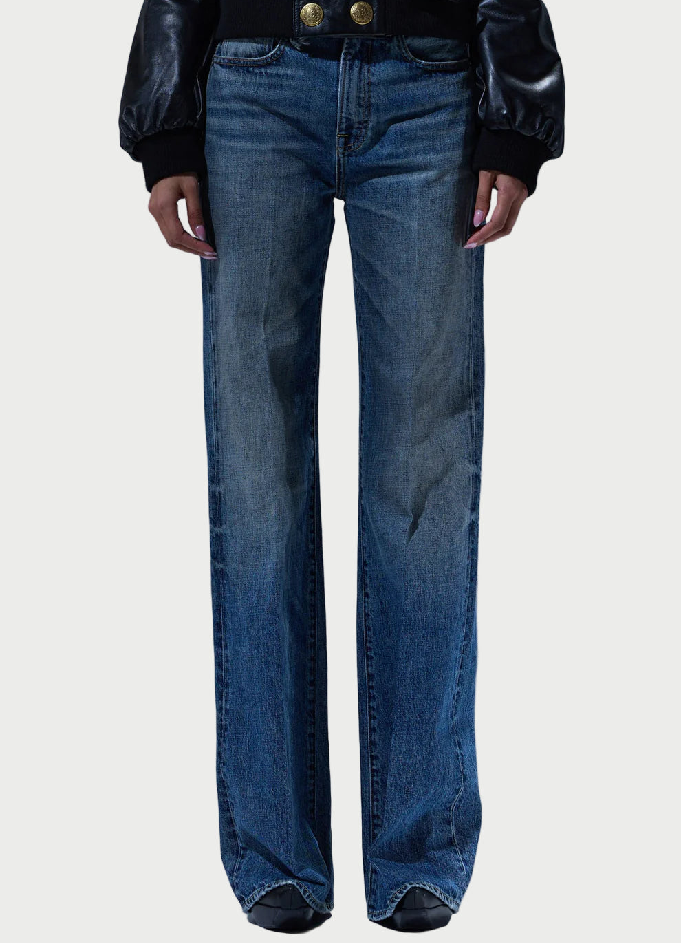 Person wearing blue jeans and a black leather jacket on a plain background