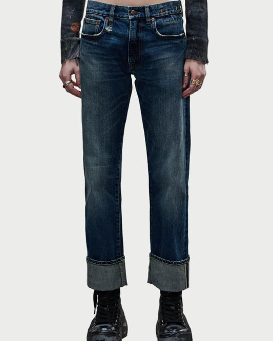 Model wears R13 Cuffed Romeo Caslon Selvedge Blue jeans in a slim boyfriend fit, paired with black boots and a dark distressed long-sleeve shirt, shown waist to feet against a plain white background.