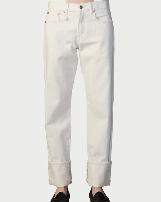 Person wearing light-colored jeans standing against a textured wall.