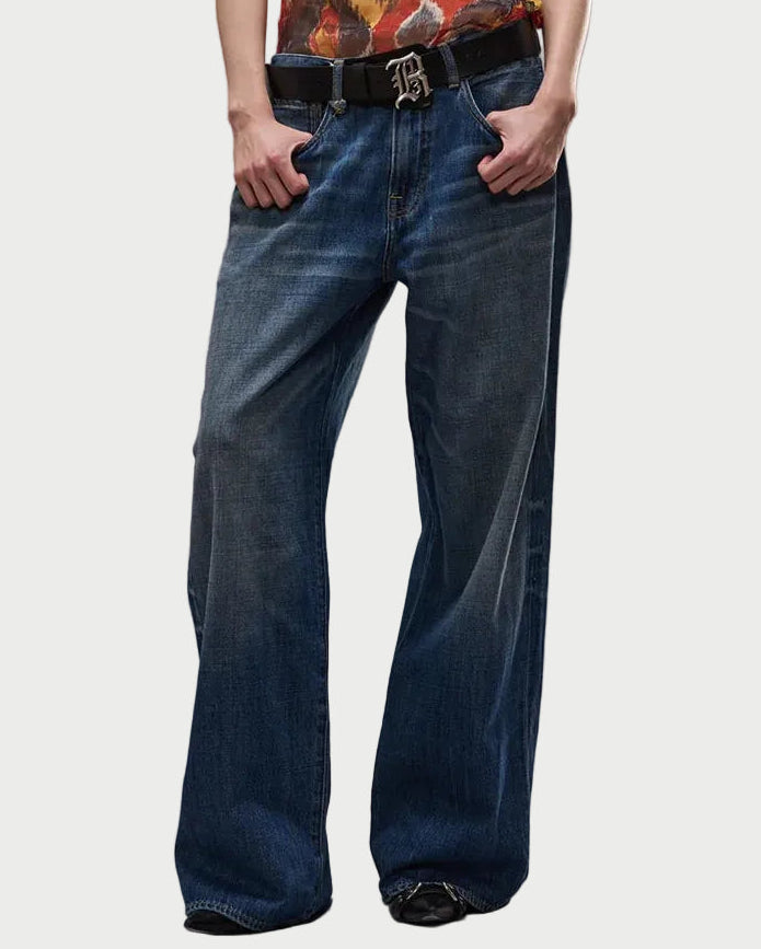 Person wearing a patterned tank top and blue jeans on a gray background