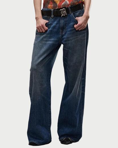 Person wearing a patterned tank top and blue jeans on a gray background