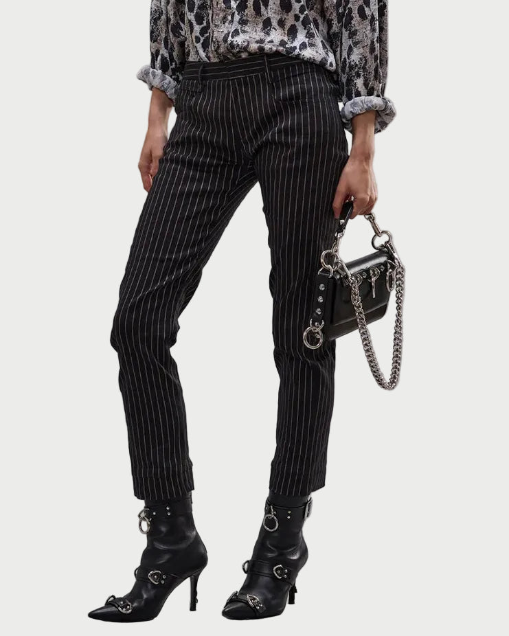 A person wears R13 Tailored Boy Straight Pant in Italian stretch linen, a patterned long-sleeve shirt, black heeled boots with silver buckles, and holds a small black chain-strap handbag.