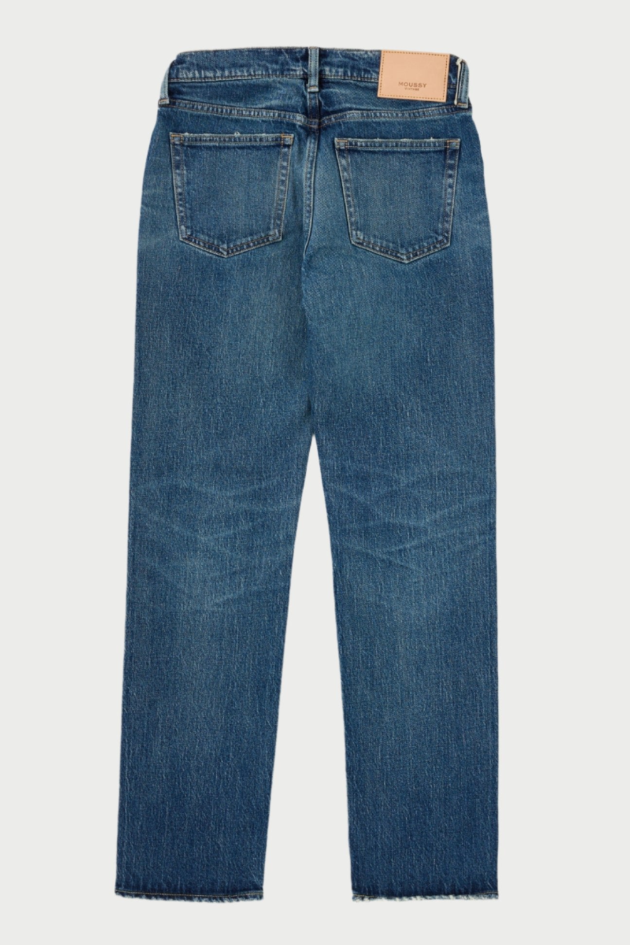 The Florahome Slim Straight Jeans by Moussy are displayed flat on a white surface, showcasing the back. These mid-rise blue denim jeans feature two back pockets, a tan leather brand patch on the waistband, and boast a slightly faded, worn look that emphasizes their heavy weight denim quality.