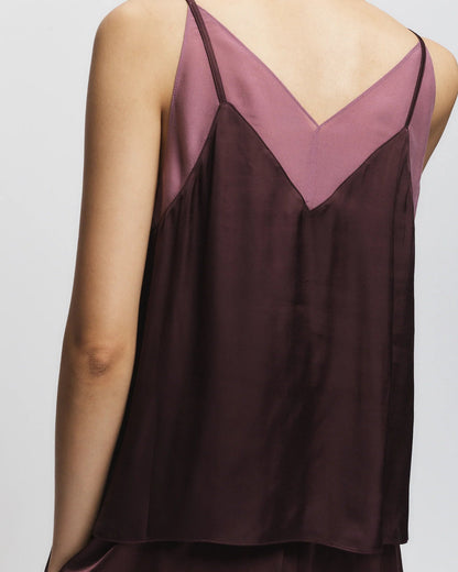A person wearing the Saint Art NY Odin Camisole in Grape, a dark burgundy viscose top with thin straps and a V-shaped back, reveals a mauve underlayer with a matching V-neckline.