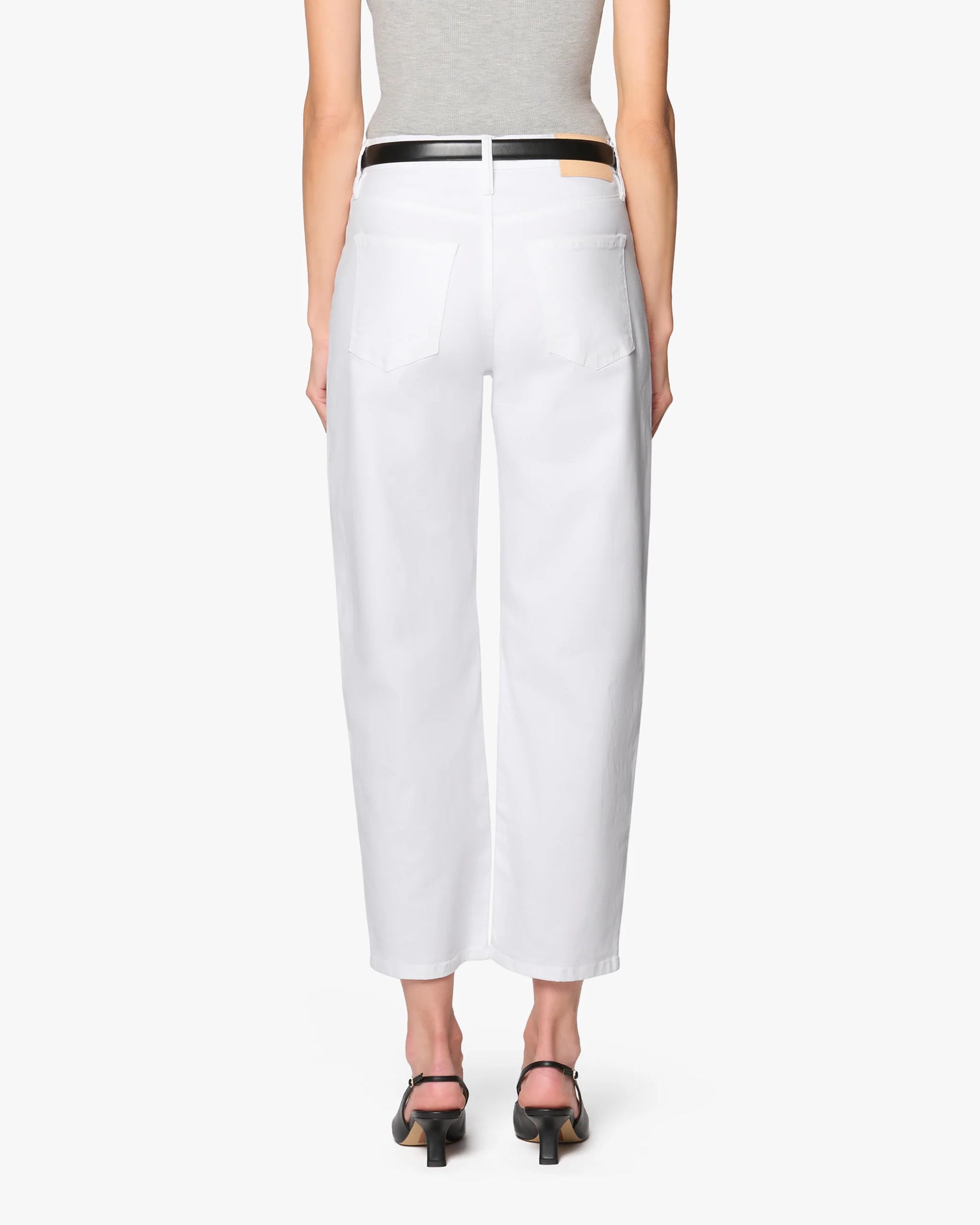 A person is shown from the back against a plain white background, wearing a gray sleeveless top, black belt, black open-toe heeled sandals, and the Ellen Bow Leg Pant by Betro Simone in white premium fabric.