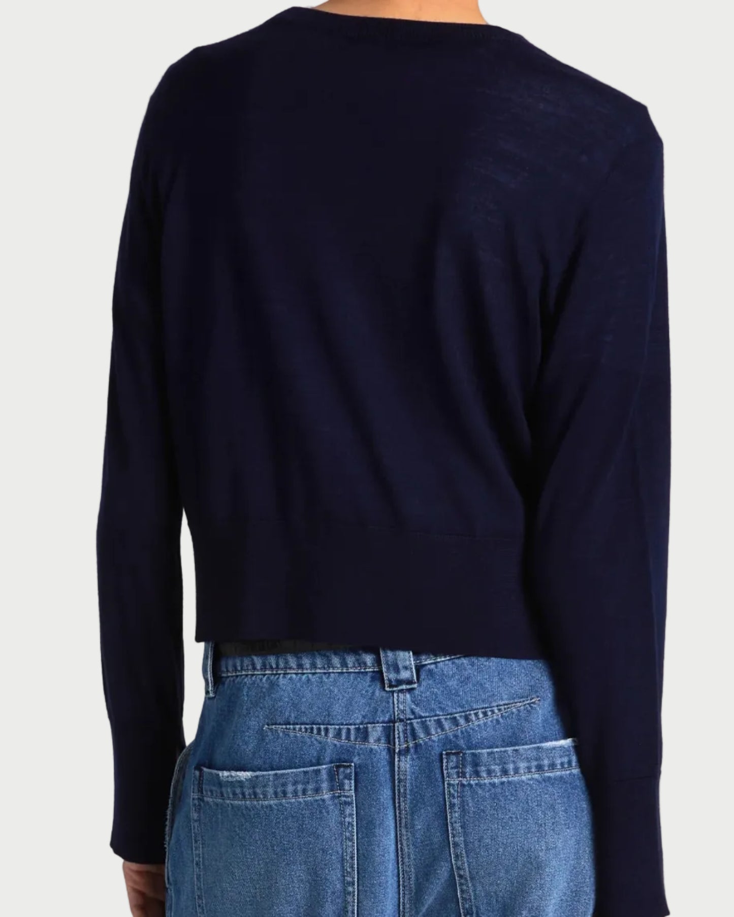 A person is shown from the back against a plain background wearing blue jeans and the Saint Art NY Elodie Sweater Navy, a long-sleeve merino wool sweater.