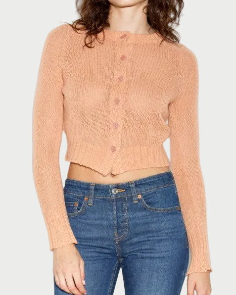 Person wearing a peach cardigan and blue jeans on a white background