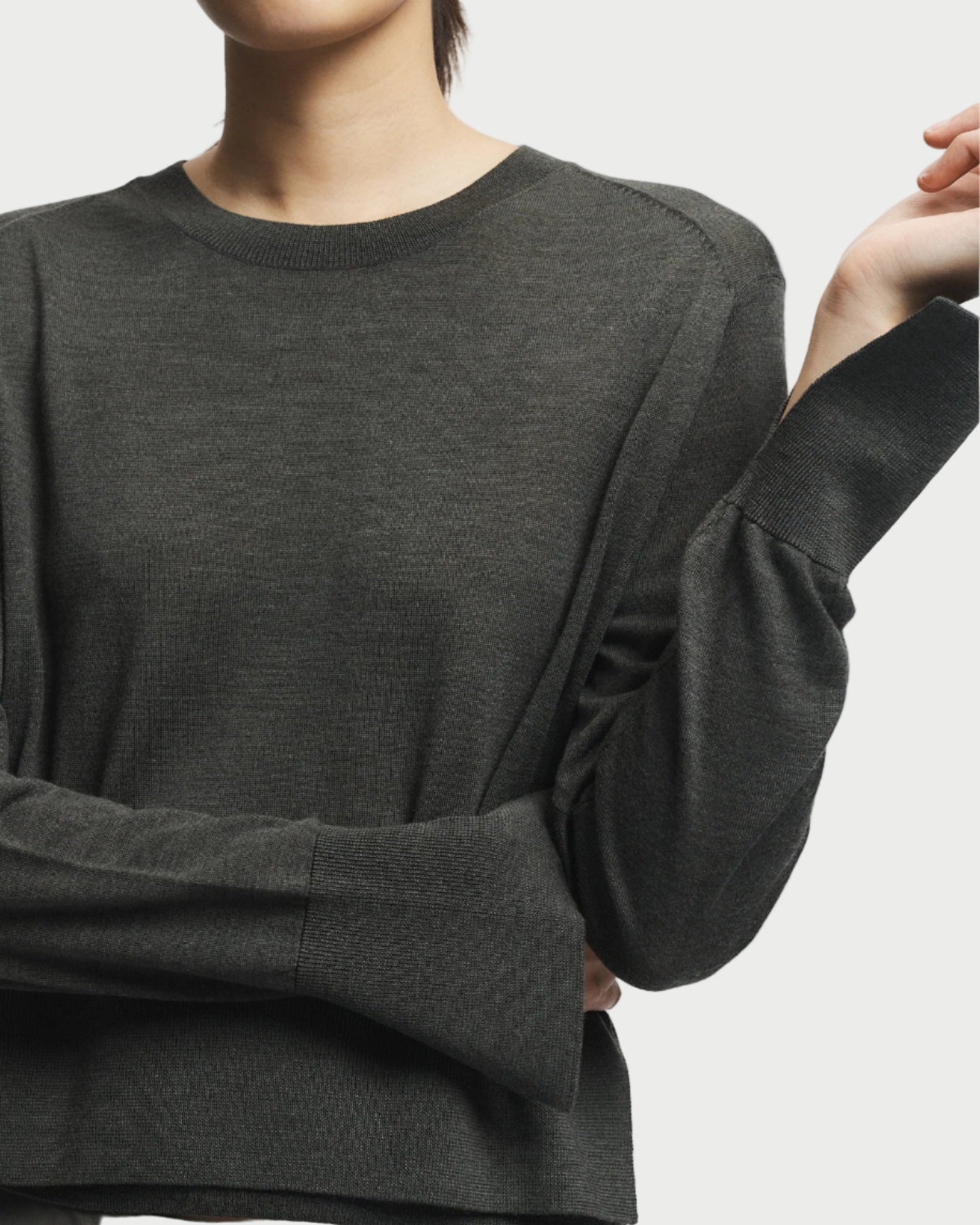 Person wearing a dark gray long-sleeve shirt against a plain background