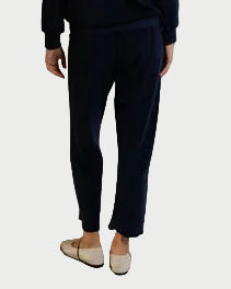 Person wearing a navy blue outfit against a white draped fabric background