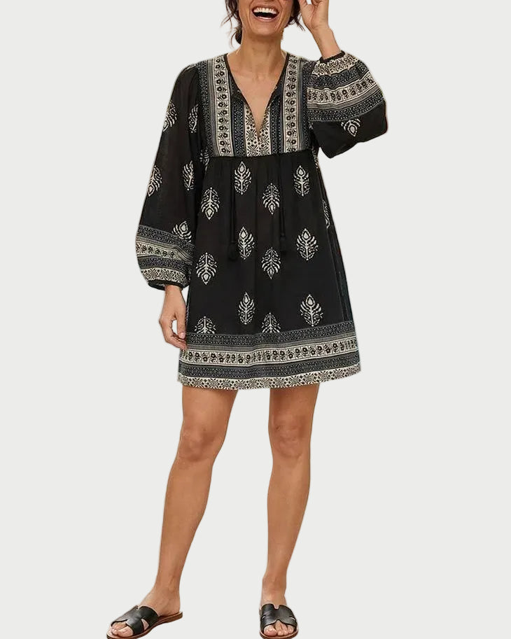 Woman in a black patterned dress standing by a pool with palm trees in the background