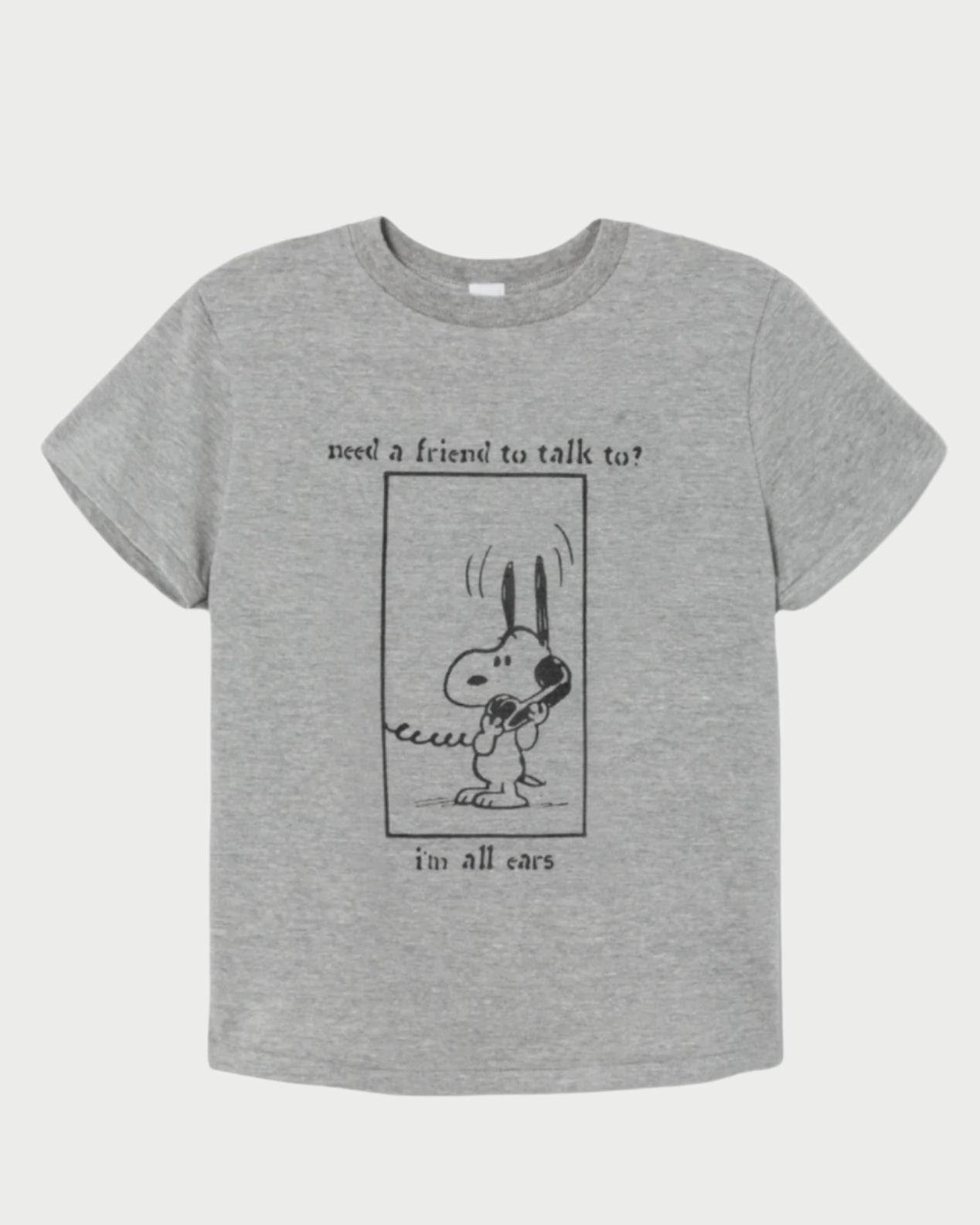 The Snoopy All Ears Tee by RE/DONE showcases the lovable cartoon dog holding a phone, with the phrase "need a friend to talk to? i'm all ears" in a rectangular frame, offering timeless style and an attentive vibe.