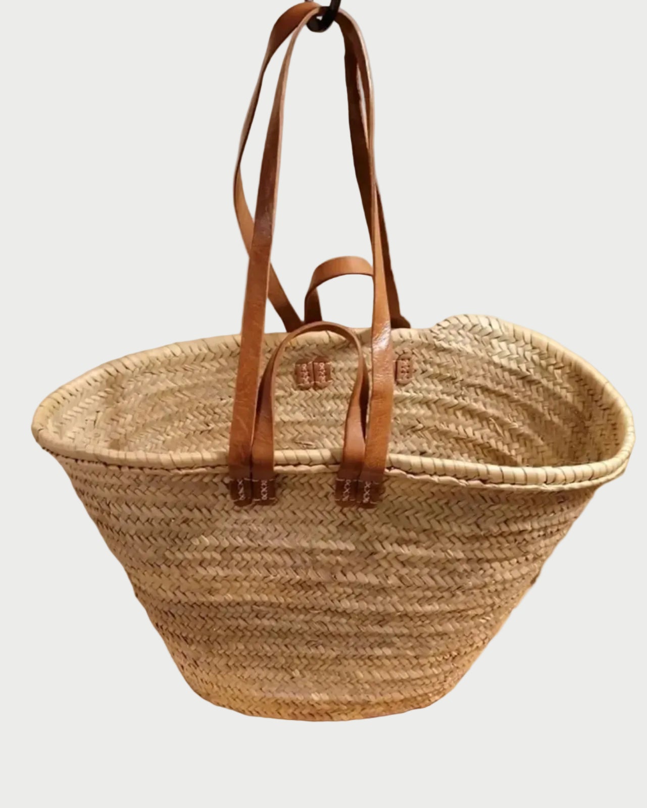 The WEST X WEST Straw Tote by West X West features two long brown leather handles and a handwoven straw design, making it an eco-friendly choice for daily use. Shown against a white background.