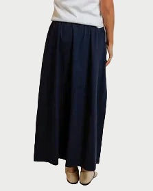 Person wearing a white strapless top and navy skirt against a plain background