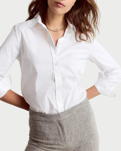 Woman wearing a white shirt and gray pants on a plain background