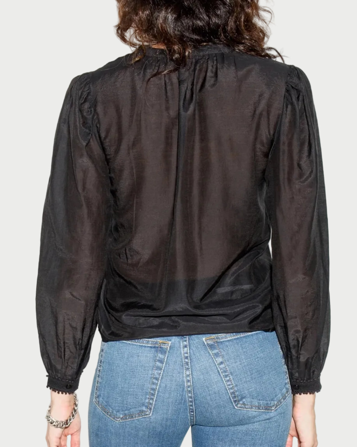 Person wearing a black blouse and blue jeans against a white background