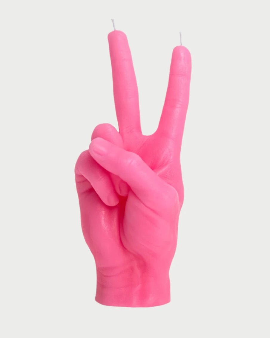 A pink, handmade Candle Hand Victory "Peace" by 54° Celsius in the shape of a life-sized hand making a peace sign. The hand boasts a naturalistic design with detailed fingers and knuckles. Two wicks are placed at the tips of the raised index and middle fingers, perfect as unique Spring decor. The background is plain white.