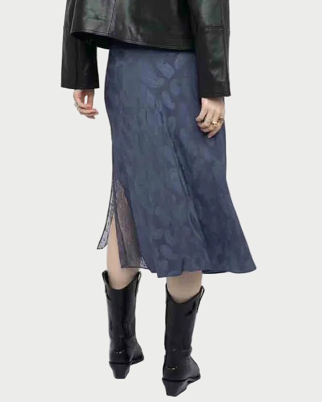 A person in a black leather jacket, Zadig & Voltaire Jayla Paisley Skirt with a side slit, and black cowboy boots is shown from the back against a plain background.