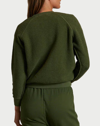 Person wearing a green tracksuit standing against a plain wall.