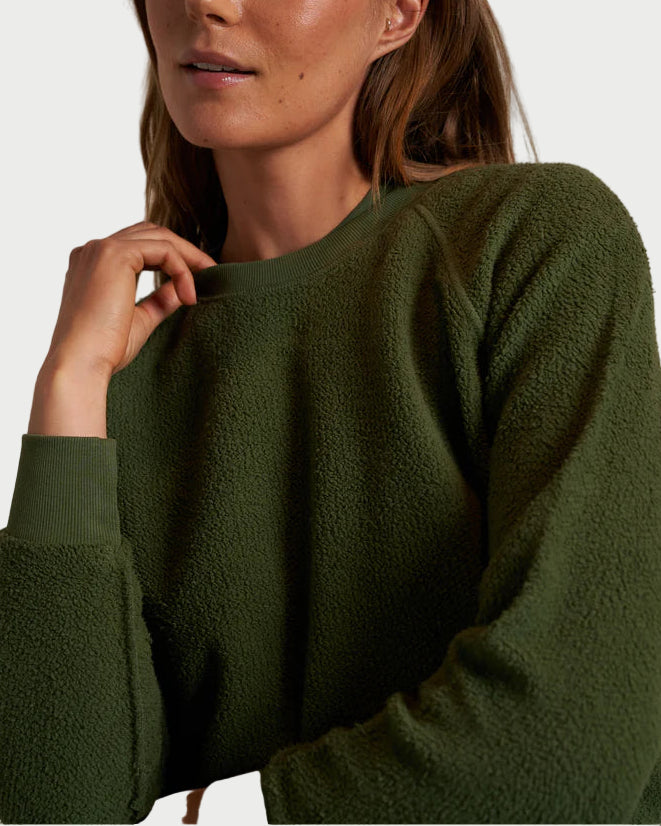 Woman wearing a green sweater against a neutral background