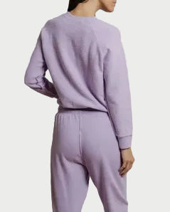 Person wearing a lavender tracksuit against a plain background