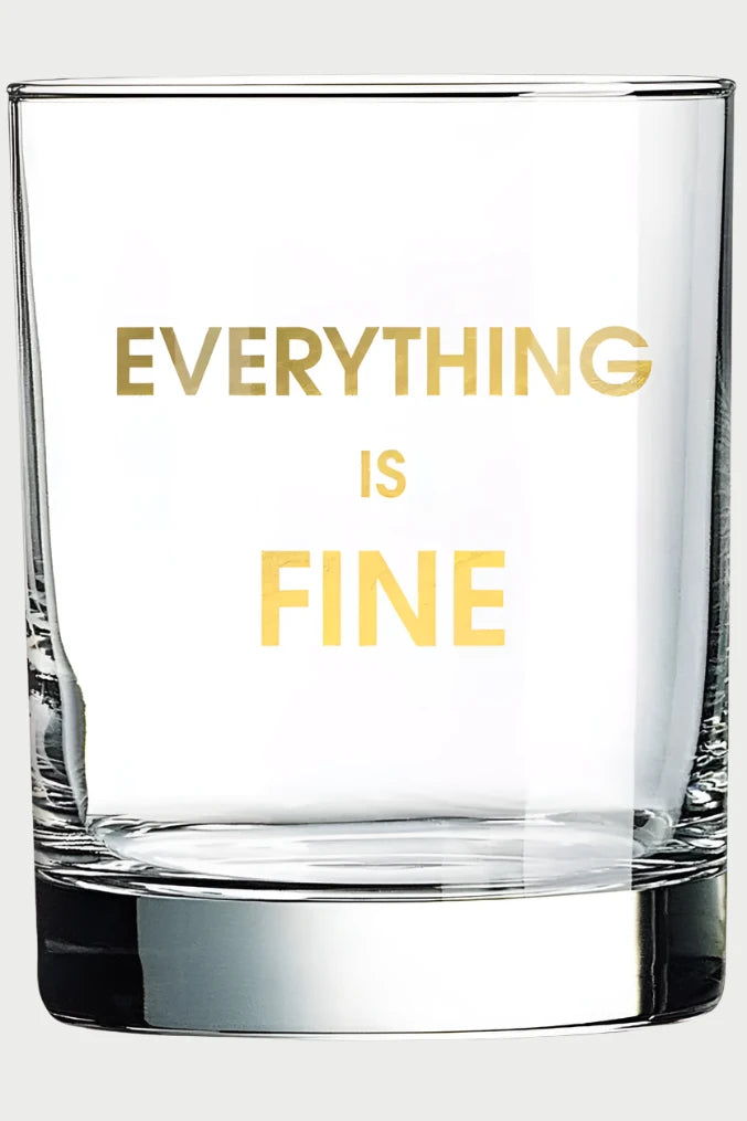 The Chez Gagné Rocks Glass, featuring "EVERYTHING IS FINE" in bold, gold foil on clear glass, is perfect for cocktails and makes a unique gift when set against a light background.